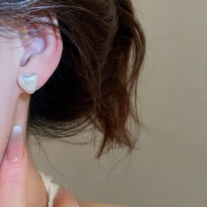 Elegant heart-shaped pearl stud earring for women shown in close-up wearing detail