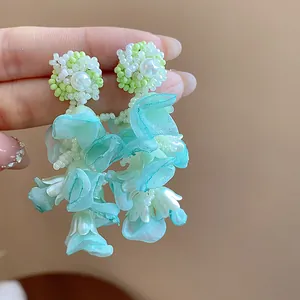Detail of light blue chiffon flower petals and beadwork on elegant silver needle earrings.