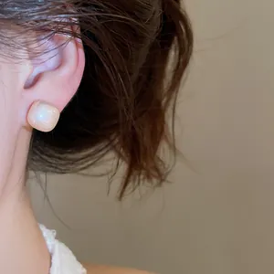 Close-up view of elegant geometric pearl stud earrings worn for a minimalist daily look
