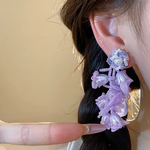 Close-up detail of elegant purple chiffon flower earrings with pearl and beadwork