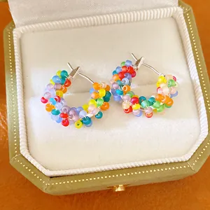 Detailed view of handmade colorful beaded hoop earrings in a green velvet box