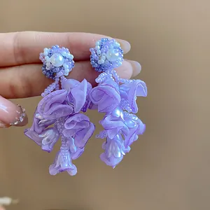 Detailed view of elegant purple chiffon flower earrings featuring pearls and silver needles