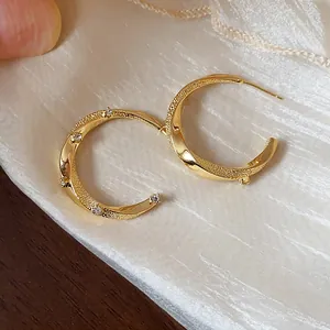 Detailed macro shot of 18k gold plated C-shaped hoop earrings with sparkling zirconia