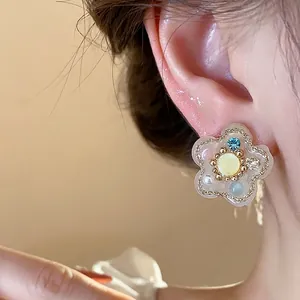 Elegantes pendientes de flor de resina con circón y perlas usados por una modelo