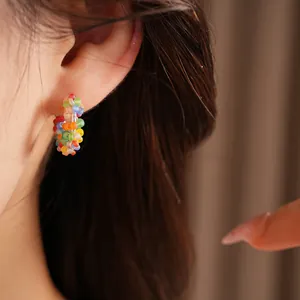 Detailed close-up view of a colorful rainbow beaded hoop earring worn on a model's ear