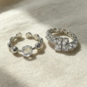 Dettaglio macro di eleganti anelli in argento con scintillanti pietre di zircone su tessuto