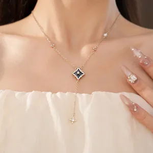 Detailed close-up of an elegant gold rhombus starburst necklace with zircon on a model