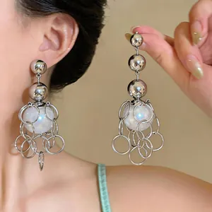 Detailed view of oversized French retro pearl earrings with silver rings and tassels