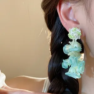 Close-up of elegant mint green chiffon flower earrings with pearl and bead detailing