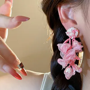 Detailed view of pink chiffon flower and pearl drop earrings worn on ear