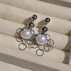 Close-up detail of silver French retro earrings with white pearls and metal ring fringe.