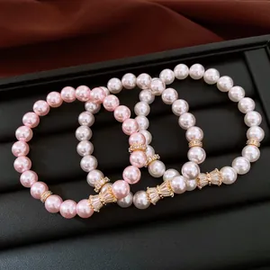 Dettaglio di eleganti braccialetti in perle rosa e bianche con distanziatori in zircone.