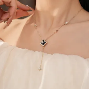 Elegant gold necklace with black rhombus pendant and star charms on an Asian model.