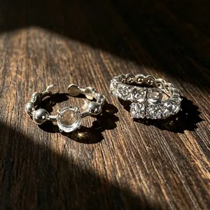 Primo piano dettagliato di anelli argentati minimalisti con zirconi su sfondo in legno scuro