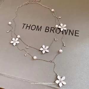 Elegante collana argentata a strati con fiori in smalto bianco perle e cristalli.