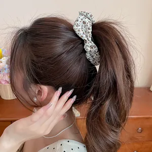 Detailed close-up showing a vintage floral bow banana clip hair accessory in a ponytail