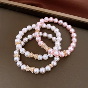 Primo piano di eleganti bracciali elastici con perle e zirconi e ciondoli a fiocco