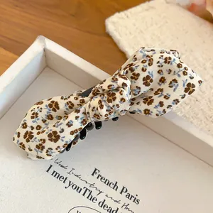 Detailed macro view of a floral print bow banana hair clip with elegant fabric texture.