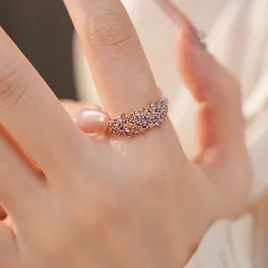 Close-up detail of a delicate rose gold ring with purple zirconia stones on a finger