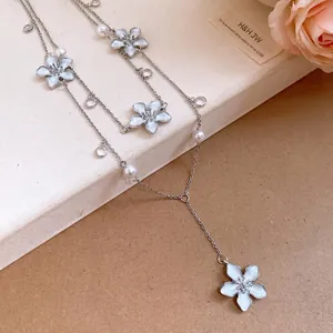 Elegante collana di perle e cristalli con ciondoli a forma di fiore azzurro oliato.