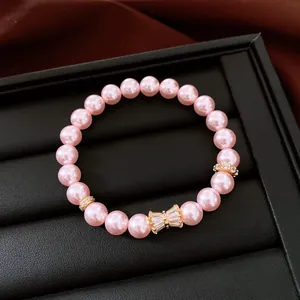 Primo piano di bracciale di perle rosa con fiocco in zircone su vassoio portagioie.