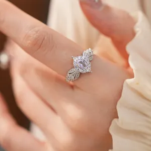 Close-up of elegant silver ring with pink oval zircon and vintage wing details.
