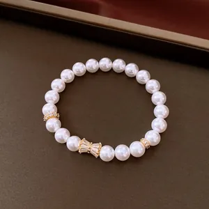 Elegante bracciale di perle con fiocco in zircone dorato su sfondo marrone scuro