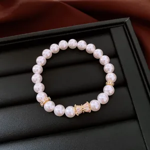 Dettaglio macro di bracciale di perle bianche con elemento a fiocco in zircone