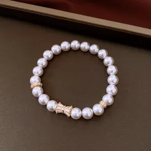 Primo piano di un elegante bracciale di perle bianche con fiocco in zircone dorato