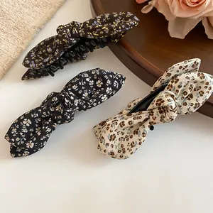 Close-up detail of three elegant floral bow banana hair clips in various patterns and colors