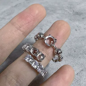 Primo piano di tre anelli minimalisti color argento con dettagli in zircone sulle dita