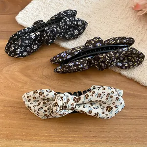 Macro view of three floral bow banana hair clips in black, coffee, and cream colors