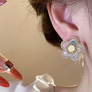 Primer plano de un pendiente de flor de resina con perlas y circonitas de colores