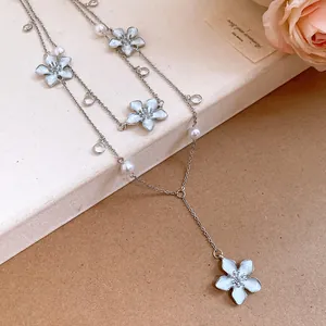 Vista dettagliata della collana a fiori vintage con perle e cristalli su base beige