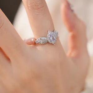 Close-up of elegant silver ring with oval pink gemstone and cubic zirconia wings
