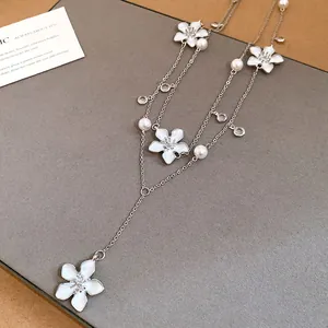 Primo piano di un'elegante collana d'argento con fiori in smalto bianco e perle