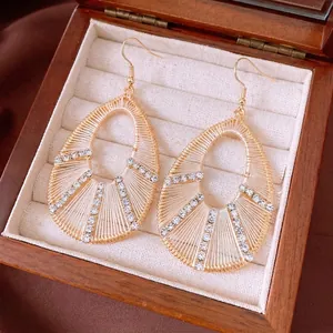 Elegant gold-tone teardrop pendant earrings with woven thread and sparkling rhinestones