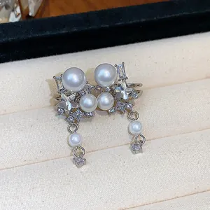 Detailed close-up of Korean style star pearl ear clips with zircon accents in jewelry box.