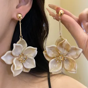 Primer plano de pendientes de flores de mármol beige con centro de diamantes dorados