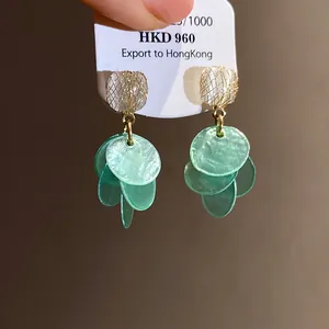 Close-up of green cat-eye stone tassel earrings with gold mesh studs