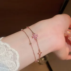 Detail of a double-layer rose gold bracelet with a pink zirconia flower.