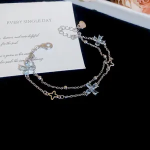 Close-up of double-layer silver bracelet with clear flower-shaped zircon charms