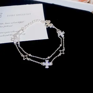 Detailed view of a silver double-layer bracelet with sparkling zircon clover charms
