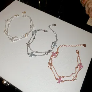 Detail of double-layer zircon bracelets with four-leaf flower charms on white display.