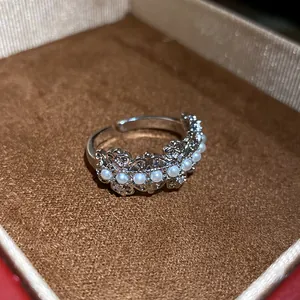 Close-up detail of a minimalist silver hollow open ring with pearls and sparkling zircons