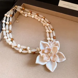 Primer plano de collar de perlas multicapa vintage con gran colgante de flor jaspeada