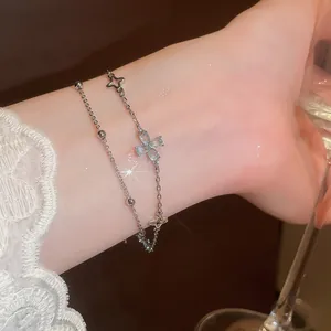 Close-up of elegant double-layered silver bracelet with blue zircon flower charm on wrist.