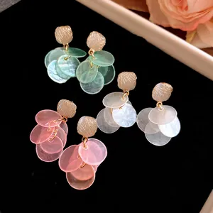 Detail view of cat eye stone stud earrings with dangling translucent colorful discs