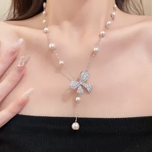 Detail view of bow pendant necklace with zircon and pearls on clavicle chain