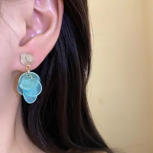 Detailed close-up of elegant blue cat's eye tassel stud earrings worn on a human ear